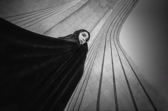 A hooded figure draped in flowing black fabric peers upward against a textured, stone-like backdrop in this monochromatic composition titled *"A Silence That Touches the Sky,"* presented as a 1/1 NFT open for offers on transient.xyz. The dramatic low-angle perspective and stark contrast evoke a sense of quiet reverence, visually echoing the contemplative mood implied by the title.