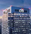 A tall office building with 'citi' branding illuminated in red against a twilight sky.