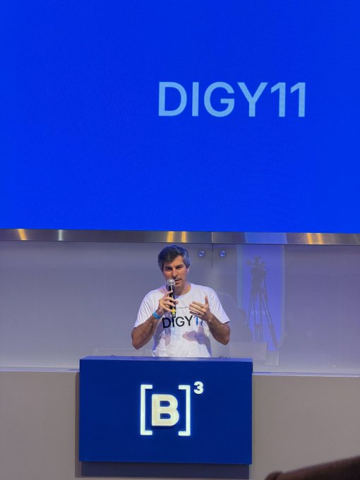 A man speaking at a podium during a DIGY11 event, with Bitget's [B]³ logo displayed prominently on the blue background and podium.