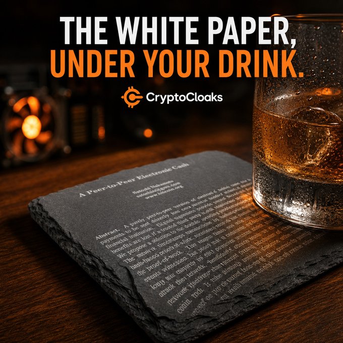 A glass of whiskey rests on a laser-etched Bitcoin slate coaster displaying the "Peer-to-Peer Electronic Cash" white paper, with bold text reading "THE WHITE PAPER, UNDER YOUR DRINK" and the CryptoCloaks logo. The image visually reinforces the caption's clever wordplay by literally showing the Bitcoin white paper placed underneath a drink.
