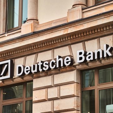 The image shows the exterior signage of "Deutsche Bank" displayed on the facade of a stone building, with the bank's distinctive square logo visible. This relates to the news about Germany's largest bank preparing to launch crypto custody services for institutional and corporate clients, starting with Bitcoin and Ether.
