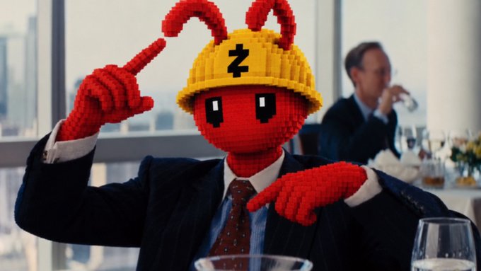 A person in a business suit has their head replaced with a red LEGO-style bug character wearing a yellow hard hat, sitting at what appears to be a formal dinner.