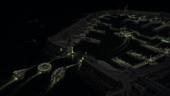 A dark sci-fi cityscape or industrial complex illuminated by glowing green lights along roads, structures, and pathways, viewed at night.