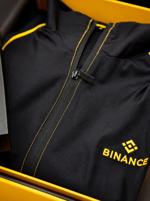 A black jacket with yellow accents and the Binance logo is shown, hinting at the opportunity to win it through learning as suggested by the accompanying post.
