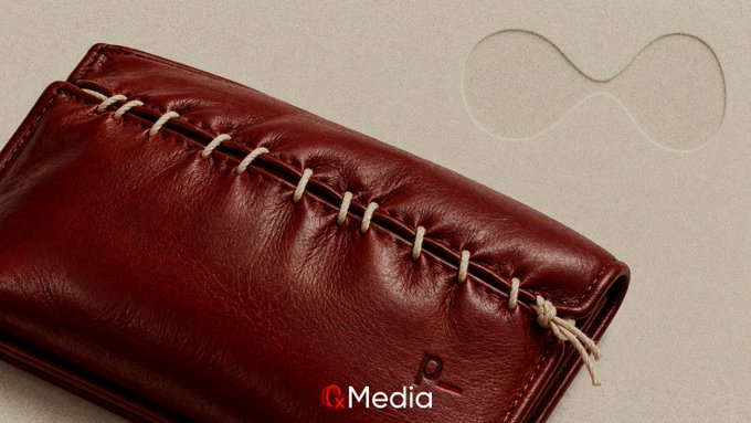 A close-up of a maroon leather wallet featuring decorative stitching along its edges, with a 'QMedia' watermark visible.
