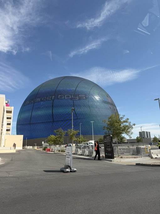 A blue-tiled spherical arena displays the text "LAS VEGAS DOLLS" against a partly cloudy sky, likely referencing the Las Vegas Sphere venue mentioned in the post, where the user humorously aims to project "WIF" in place of other content.