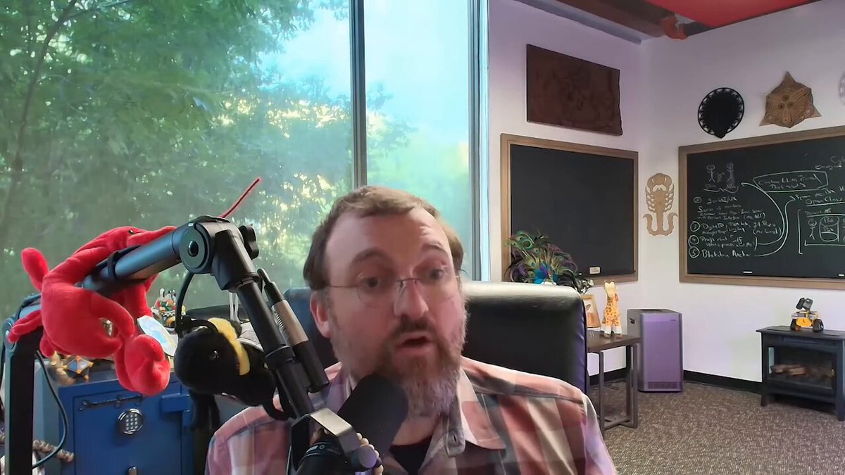The image features a man wearing glasses sitting behind a microphone, likely participating in an online radio show or podcast. The man appears to be discussing the importance of the partner chain model, which is a key concept in blockchain technology. He explains that with this model, users can plug in state-of-the-art solutions without having to change anything on their devices. This allows for flexibility and adaptability in implementing new technologies or applications. The image also includes a reference to "Cardano" as an example of a company that has successfully implemented the partner chain model into its platform.