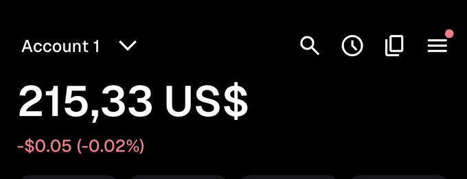 A dark-themed financial app screen showing an account balance of 215,33 US$ with a small decline of -$0.05 (-0.02%), under the header 'Account 1'.