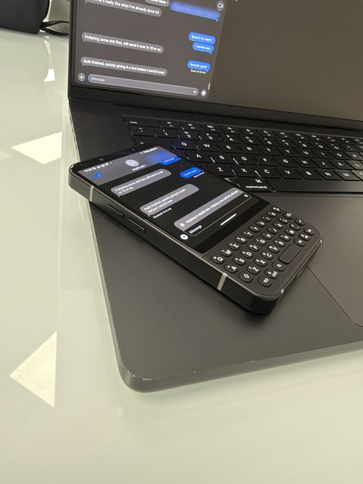 A black smartphone with a physical keyboard rests on top of a laptop keyboard, with both screens displaying text message conversations.