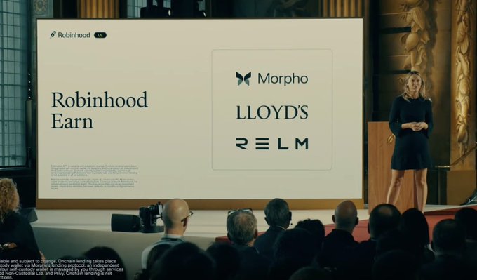 A woman in a black dress presents on stage at a financial conference, with a large screen displaying "Robinhood Earn UK" alongside logos for Morpho, Lloyds, and RELM. The presentation showcases Robinhood's new UK lending product partnered with Lloyds bank, illustrating the company's strategic expansion into the British fintech market beyond its U.S. crypto-trading origins.