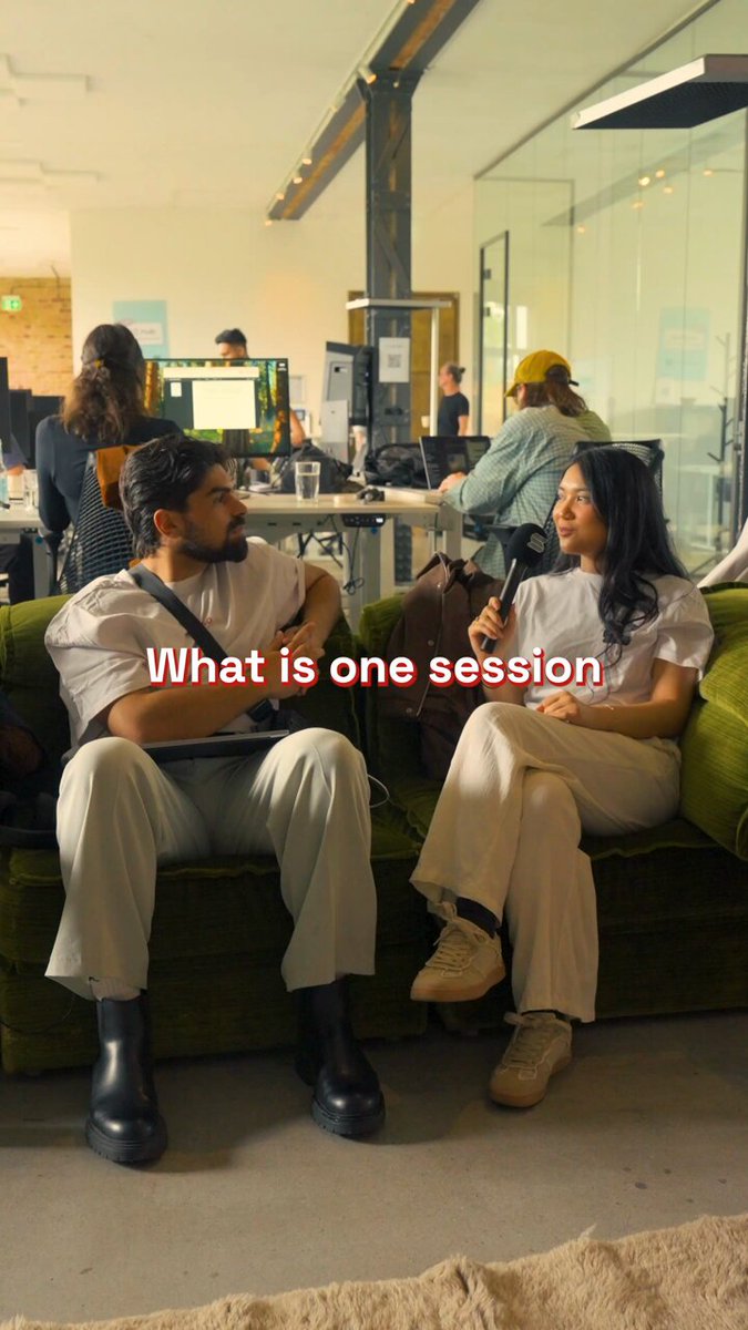 The image shows a man sitting on a couch with his legs crossed, while a woman sits next to him. They appear to be engaged in conversation or discussing something together. In the background, there are other people present as well. The caption for this image reads "The full agenda for the @Solana Summit Germany is here Insights. Experiences. Connections. See the conference agenda and tell us what you are most excited for in the comments?".