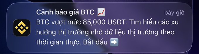 A Binance notification in Vietnamese reading 'Cảnh báo giá BTC: BTC vượt mức 85,000 USDT' (BTC price alert: BTC exceeds 85,000 USDT).