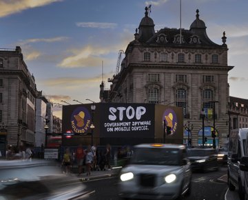 A censored billboard in Piccadilly Circus, London, reads "ST... GOVERNMENT SPYWARE ON MOBILE DEVICES," with the Mullvad VPN logo visible, highlighting the post's message about privacy concerns and Mullvad's anonymous payment options.