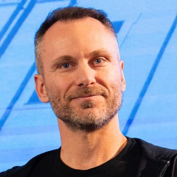 The image shows Paolo Ardoino, CEO of Tether, speaking at an event with a blue geometric background featuring the Tether logo. The accompanying post reflects his commentary on the challenges facing AI infrastructure, highlighting shrinking margins, diminishing returns on capital expenditure, and growing pressure from open-source alternatives on established industry players.