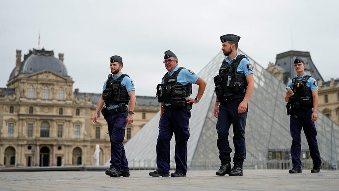 Four French gendarmes stand in formation in front of the Louvre Museum, symbolizing the physical security concerns raised by the recent French tax data breach affecting 678,000 individuals and businesses.