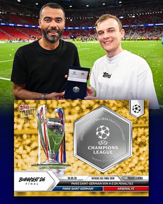 The image features two men standing next to each other with a coin between them. The coin has a picture of the Champions League logo on it and is described as an "official match coin" that started the UEFA Final in Budapest. The coin also mentions that it was preserved inside an ultra-rare relic card by @luke_solve Authenticated, which implies its historical significance.