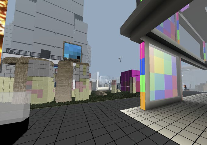 A first-person view of a blocky, voxel-style virtual environment featuring a tiled floor, a stone-textured building with a window, and a modern structure displaying colorful checkered patterns and a soft color palette.