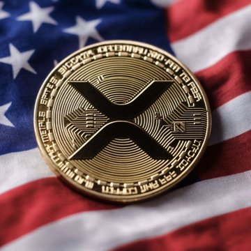 A physical representation of the XRP cryptocurrency coin rests atop an American flag, visually tying the digital asset to the post's speculation about Elon Musk's X super-app potentially integrating XRP and XLM payment features.