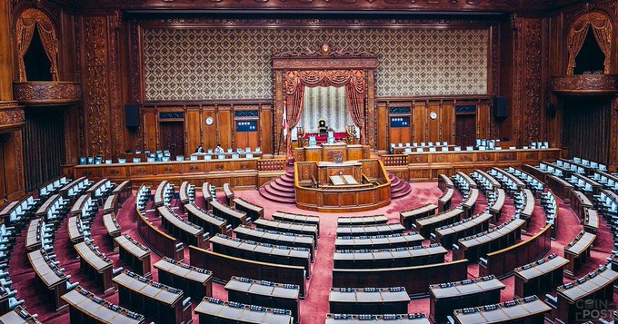 Japan's House of Councillors chamber, with its ornate wooden interior and curved rows of empty seats facing a central dais, represents the legislative setting where the revised law reclassifying cryptocurrency as a "Financial Product" was passed, introducing insider trading rules, lowering the tax rate to about 20% starting January 2028, and permitting three-year loss carryover.
