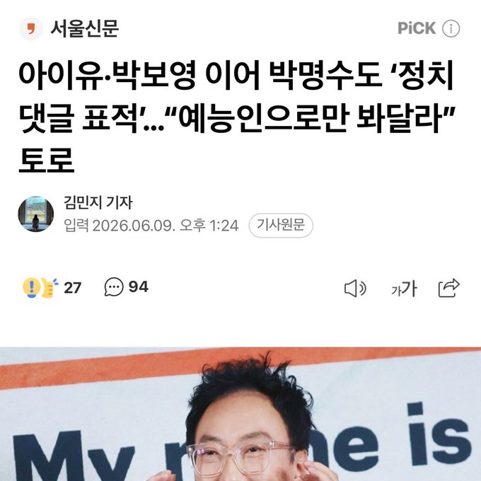 The image features a man wearing glasses, with his head tilted back as he looks at something behind him. The background of the photo shows an advertisement for My Name Is, which has been edited to include Korean text. The caption reads "Hoping to be seen just as entertainers yet you've been acting in ways up to now that make yourselves targets by making political statements— doesn't that contradict itself?".