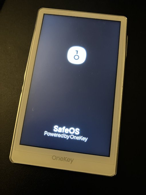 A OneKey hardware wallet device displaying the boot screen with a lock icon and the text "SafeOS Powered by OneKey" on a dark background.