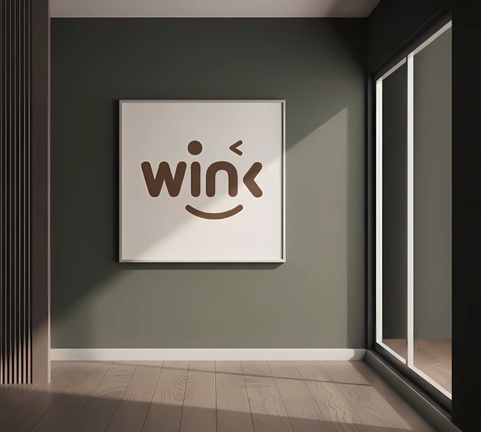 A minimalist room interior with a framed poster displaying the stylized text 'wink' on a sage green wall, illuminated by natural light from a window.