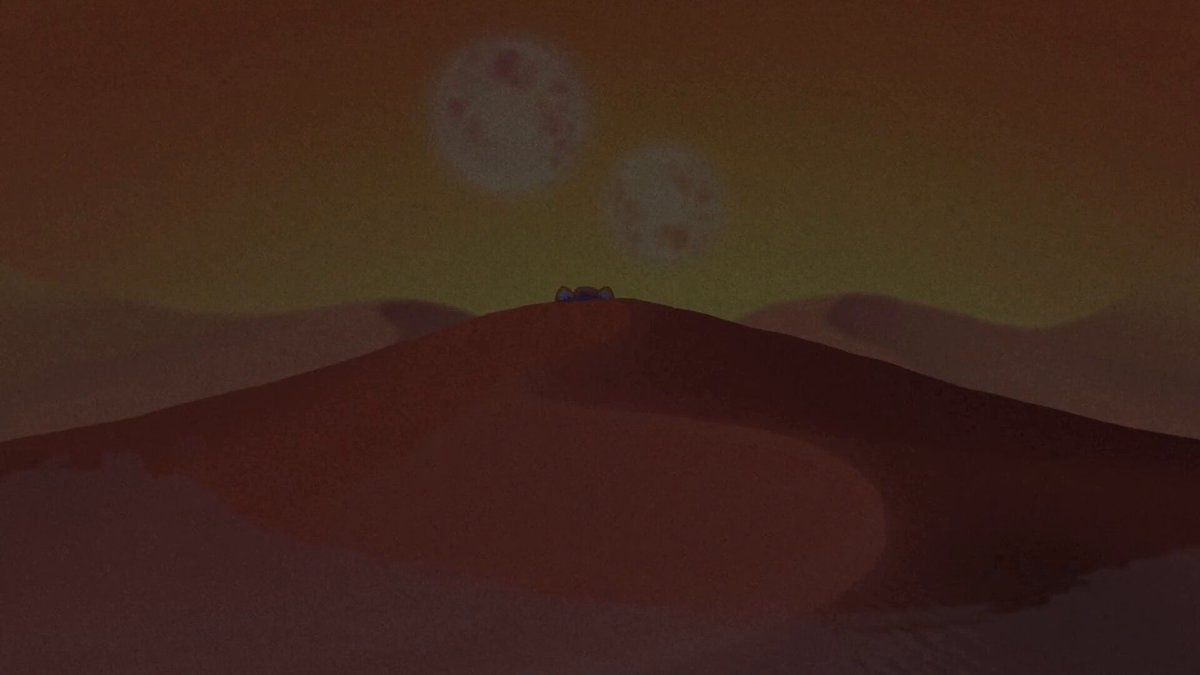 urn of gold with two white circles, one on top of the other, sitting atop a hill.