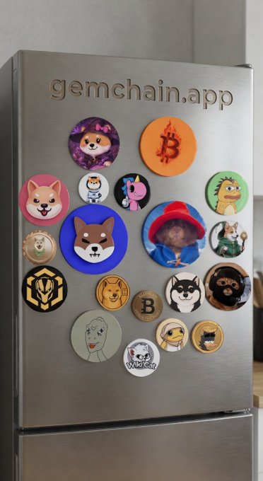 A stainless steel refrigerator displays the engraved text 'gemchain.app' at the top and is decorated with various colorful circular magnets featuring crypto coins, memes, and cartoon characters like Doge, Shiba Inu, Bitcoin, and Pepe.