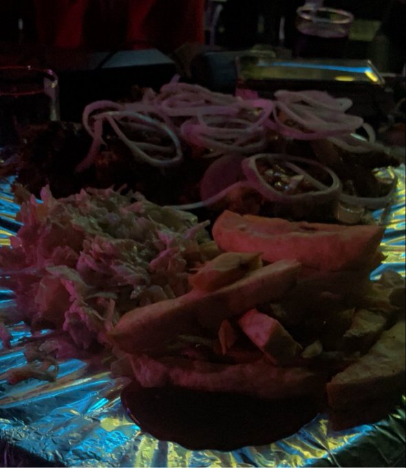 A dimly lit, blurry photo of food on foil, including what appears to be pita/flatbread with onions and other sides.