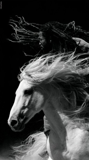 A dramatic black-and-white photograph shows a person with long flowing dreadlocks riding a galloping horse with a wild mane, both appearing to be in motion against a dark background.