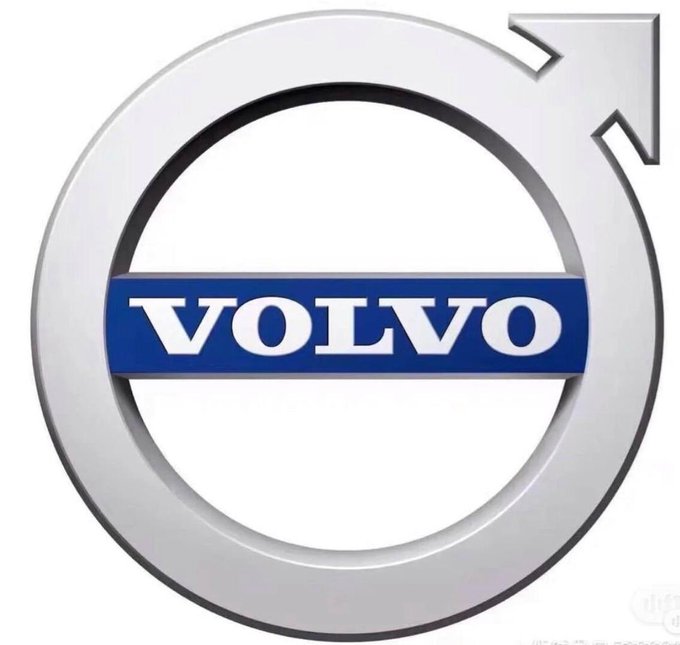The image shows the Volvo logo, featuring a silver circular arrow with a diagonal arrow extending from the top right, encircling a blue rectangular banner with "VOLVO" written in white letters. This relates to the post highlighting that the Volvo Group, a $71 billion traditional automotive company, is developing its own cryptocurrency for global supplier settlements, demonstrating crypto's real-world value and adoption by major corporations.