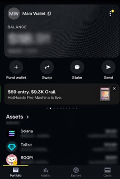 A Phantom (MW) wallet mobile interface showing a blurred balance, an NFT display for 'HoliHeads Fire Machine,' and assets including Solana, Tether, and BOOP, with bottom navigation for Portfolio, Market, Explore, and Cards.