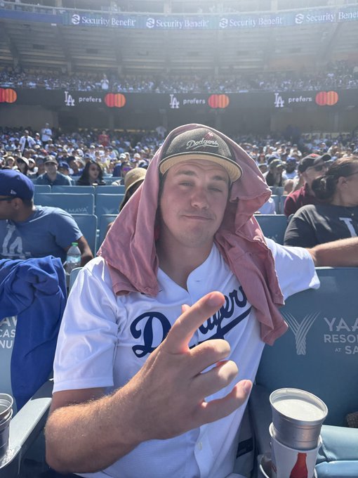 iced tea and soda are served at a Dodgers game, with a man in a white jersey and pink cap seated in the stands.