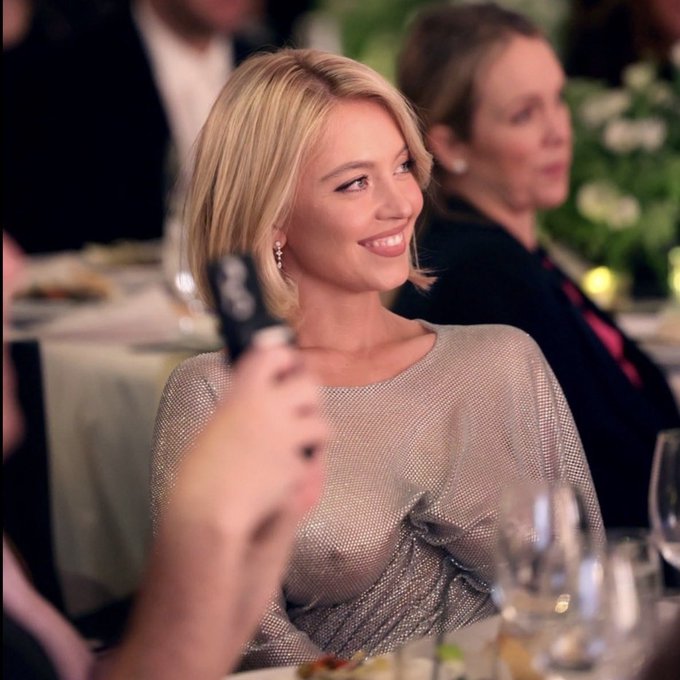 A blonde woman in a shimmering gold top smiles brightly while seated at a formal dinner event, holding up a phone in what appears to be a celebratory moment.

The image of celebration visually parallels the post's theme of investors celebrating $LIT's price movement—illustrating how market participants often react emotionally to price swings in both directions, whether rallying at "good" prices or despairing at "bad" ones, just as the caption critiques traders running the same emotional playbook regardless of price direction.