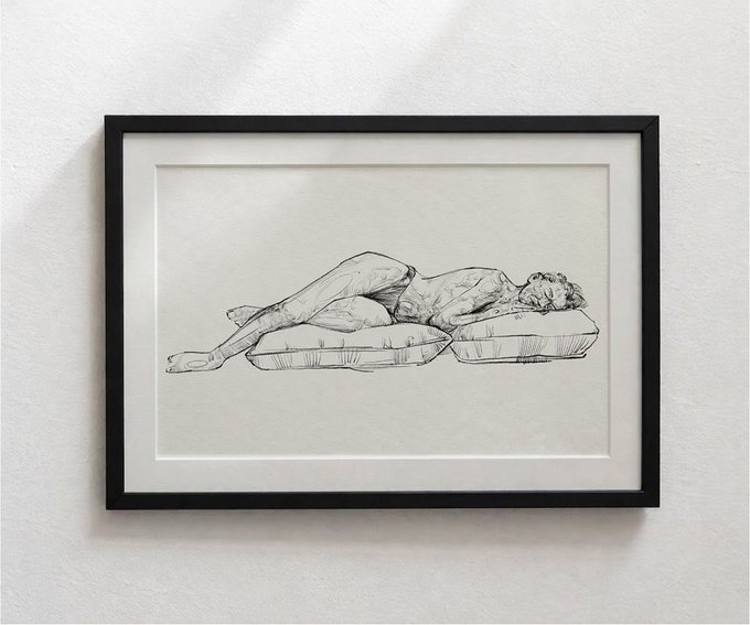 A framed pen/ink sketch hangs on a wall, depicting a reclining nude figure resting on a tufted cushion in a style reminiscent of Egon Schiele.