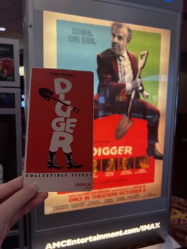 A hand holding an IMAX collectible ticket for the movie 'DIGGER', featuring a character holding a shovel, displayed in front of a matching movie poster.