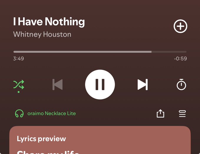 A Spotify playback screen shows Whitney Houston's "I Have Nothing" playing at 3:49 with -0:59 remaining, connected to oraimo Necklace Lite headphones, displaying a "Lyrics preview" panel at the bottom. The song title and lyrics preview "Share my life" playfully mirror the post's wordplay on having "nothing" while expressing contentment.
