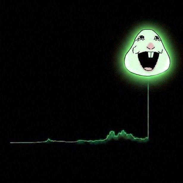 A glowing green image of a manic-looking cartoon character (the 'Crazy Face' meme) suspended on a thin vertical line above a small green blob, set against a black background.