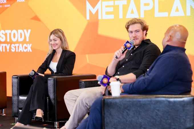 A panel discussion at the "METAPLAN" event, where three individuals are seated on stage holding microphones against a backdrop reading "METAPLAN" and "...STODY ...ITY STACK," suggesting a crypto or blockchain-focused talk featuring a speaker named BritishHodl, who is humorously known for his anti-dice sentiments.