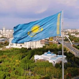 The flag of Kazakhstan waves prominently over a cityscape, symbolizing the country's recent approval of "strategic digital mining" rules aimed at building its national crypto reserve.