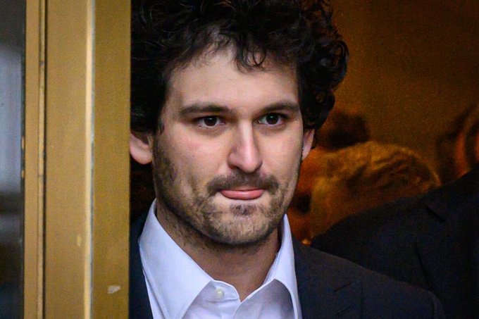A man with curly dark hair and a stubbled beard peers through a doorway, his expression serious and contemplative. The image is paired with a post about Sam Bankman-Fried, suggesting the man pictured is the former FTX founder whose failed crypto empire contrasted with his once-promising Robinhood investment.