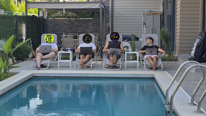 Four people relaxing on lounge chairs beside a swimming pool, each using a laptop, with their faces obscured by cryptocurrency logos.