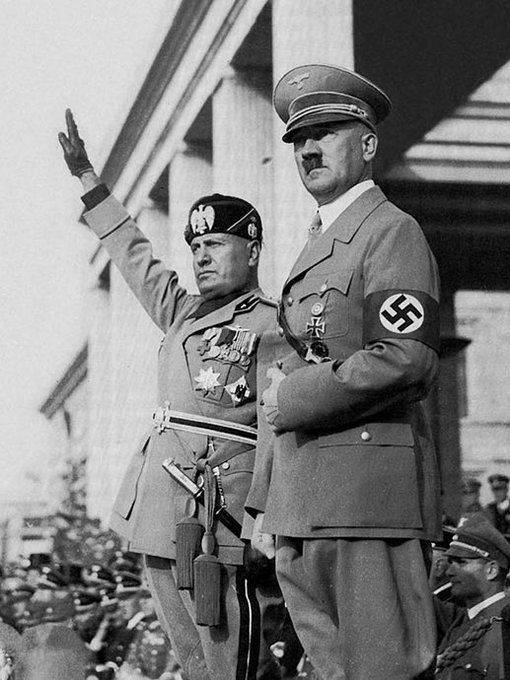 Adolf Hitler stands beside Hermann Göring, who is raising his arm in the Nazi salute.