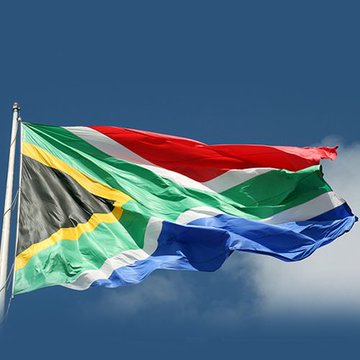 Image 2: The national flag of South Africa waving against a partly cloudy blue sky, displaying its characteristic Y-shape with red, blue, green, black, yellow and white colors.