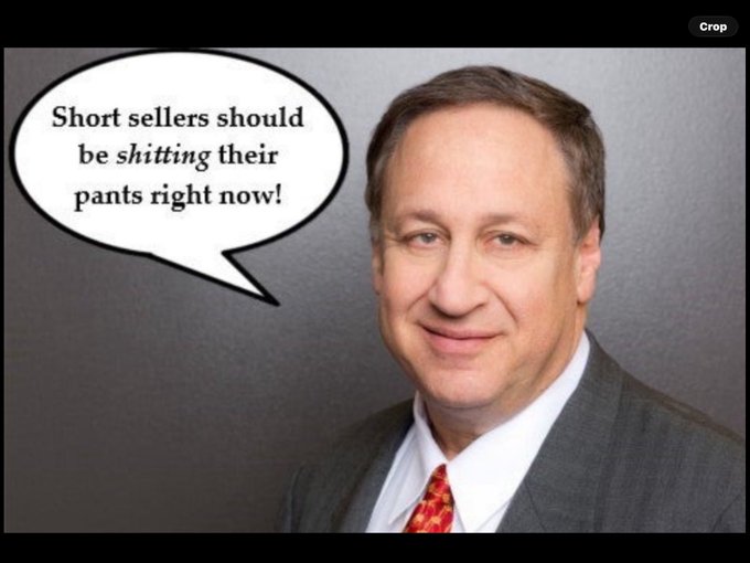 A man in a suit smiles for a portrait photo with a speech bubble pointing to him that reads, 'Short sellers should be shitting their pants right now!'