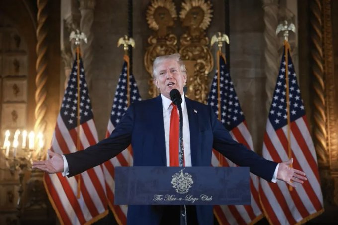 The image shows a man standing behind a podium, giving a speech or addressing an audience. The man appears to be wearing a suit and tie, suggesting that he might be a political figure or leader. There are several American flags displayed around him, indicating that this event is taking place in the United States. The post includes text about Trump calling for an investigation into Fort Knox's gold reserves, which could potentially impact Bitcoin audits.