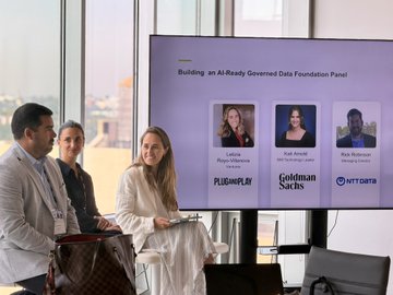 Three panelists sit at a table in front of a screen displaying "Building an AI-Ready Governed Data Foundation Panel" with headshots and names: Lahini Pandya (PLUG AND PLAY), Cathi Landis (Goldman Sachs), and Alex Robinson (NTT DATA), aligning with the XDC × Plug and Play AI Agents & Blockchain Accelerator Kickoff event featuring Goldman Sachs and NTT DATA speakers.