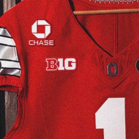A red Ohio State football jersey hangs on a wooden hanger, prominently displaying the white JPMorgan Chase logo and "CHASE" text as the official jersey patch, along with the "B1G" Big Ten Conference logo and the number 1, illustrating the new sponsorship partnership between Ohio State and JPMorganChase across its 36 varsity programs.