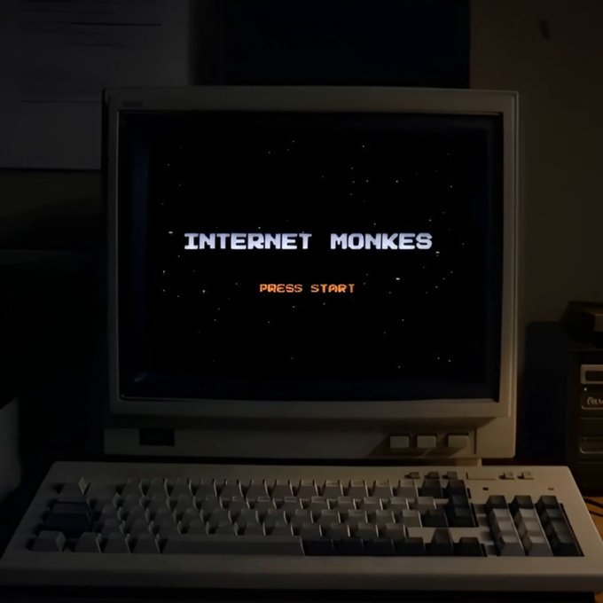 A retro CRT monitor displays the title screen "INTERNET MONKES - PRESS START" against a starry background, sitting atop a vintage computer keyboard in a dimly lit room. The image ties into the post by showcasing the title screen of the NFT collection being discussed, which is reportedly trading around 3x off its mint price.