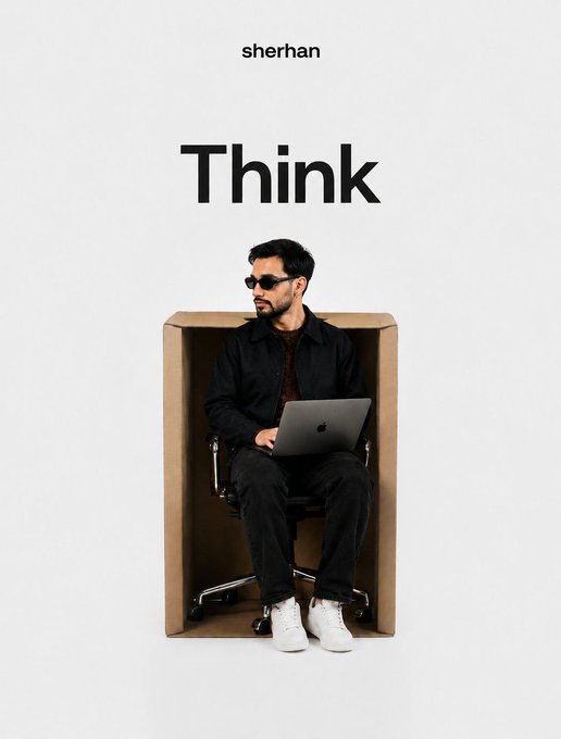 A promotional image for 'sherhan' showing a man in black clothing and sunglasses sitting in a chair inside a cardboard box while working on a laptop, with the word 'Think' displayed above.